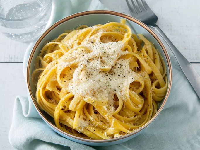 overhead view of buttered noodles in a bowl garnished with cheese